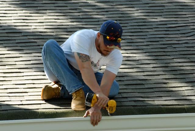 technician securing gutter to roof